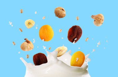 Süt sıçraması, yulaf ezmesi ve açık mavi arka planda kuru meyveler.