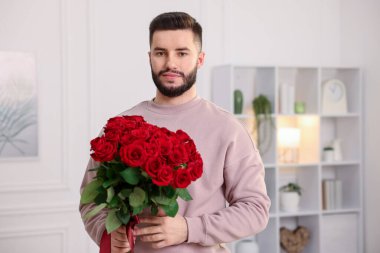 Evinde kırmızı gül buketi olan bir adam