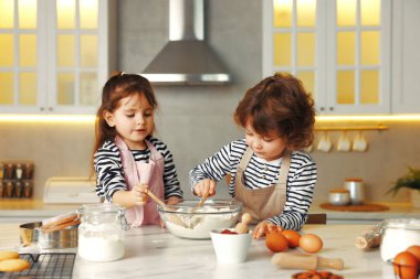 Yemek tarifi. Sevimli çocuklar mutfaktaki masada kurabiye için para kazanıyor.