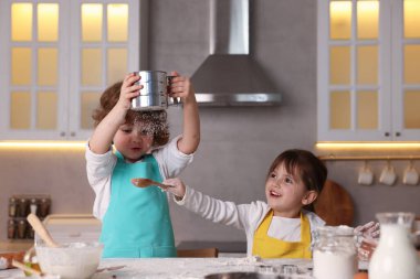 Yemek tarifi. Mutfaktaki masada un elemekte olan sevimli çocuklar.