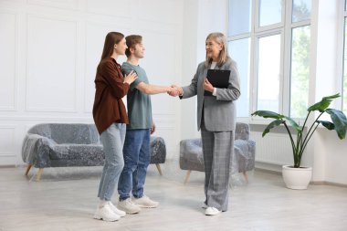 Gülümseyen emlakçı evin yeni sahibiyle el sıkışıyor.