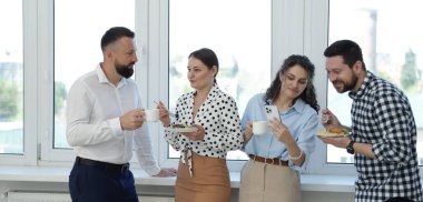 Yemek ve içeceklerle iş arkadaşları öğle arasında ofiste pencere kenarında.