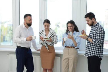 Yemek ve içeceklerle iş arkadaşları öğle arasında ofiste pencere kenarında.