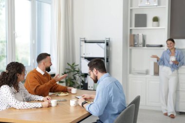 İş arkadaşları ofiste yemek yiyor ve sohbet ediyorlar.