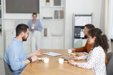 İş arkadaşları ofiste yemek yiyor ve sohbet ediyorlar.