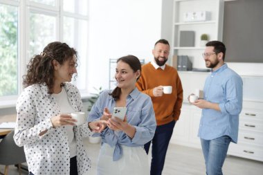 Ofiste kahve molası sırasında iş arkadaşları sohbet ediyor.