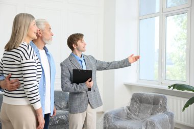 Gülümseyen emlakçı içeride çiftlere daire gösteriyor.