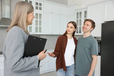 Dosyası olan bir emlakçı mutfakta bir çiftle çalışıyor.