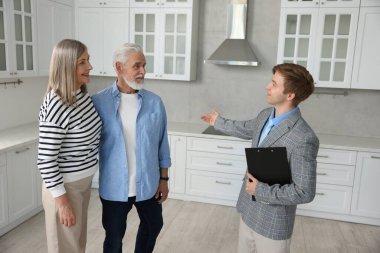 Gülümseyen emlakçı içeride çiftlere daire gösteriyor.