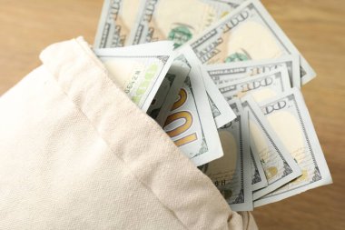 Tahta masanın üzerinde dolar banknotları olan çanta, yakın plan.