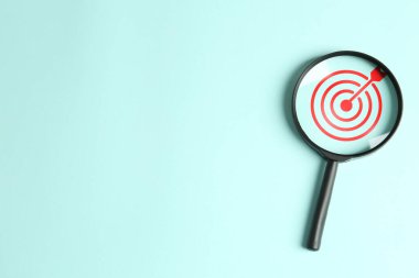 Hedef alınıyor. Açık turkuaz arka planda hedef tahtası olan büyüteç, üst manzara. Metin için boşluk