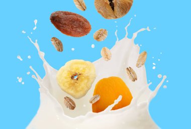 Süt sıçraması, yulaf ezmesi ve açık mavi arka planda kuru meyveler.