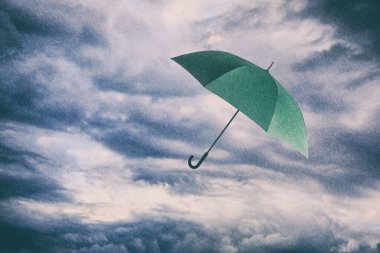 Sağanak yağmur altında bulutlu gökyüzünde uçan yeşil şemsiye. Fırtınalı hava