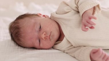 Sevimli yeni doğmuş bebek yatakta uzanıyor, yakın plan.