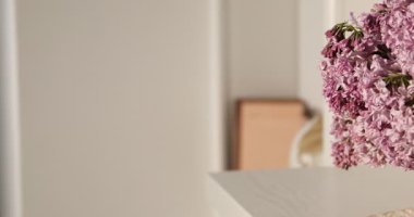 Dolabın içinde cam vazoda güzel leylak çiçekleri, kamera sağa doğru hareket ediyor.