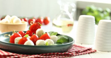 Beyaz ahşap masada mozzarella peyniri, domates ve fesleğen ile lezzetli mezeler. Kamera sola hareket ediyor