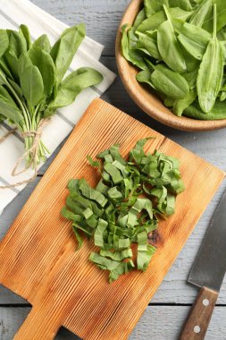 Gri ahşap masada taze kuş yaprakları ve bıçak kes, düz uzan.