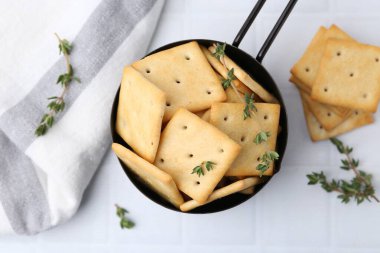 Lezzetli tuzlu krakerler ve kekik beyaz fayanslı masada, düz yerde.