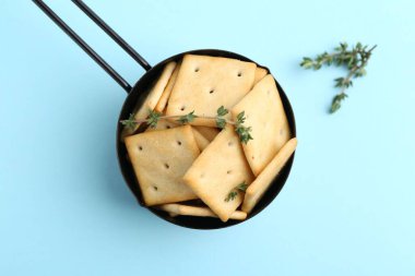 Açık mavi arka planda leziz tuzlu krakerler ve kekik, üst manzara.