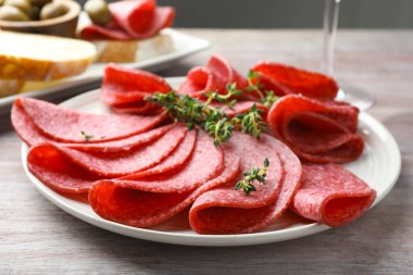 Hafif ahşap masada servis edilen kekik dilimli lezzetli sosisler.