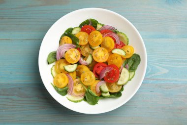 Sarı domatesli taze salata açık mavi ahşap masa, üst manzara.