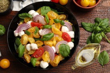 Sarı domatesli lezzetli salata, fesleğen, soğan ve ahşap masada mozzarella peyniri.