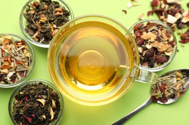 Cam fincanda nefis bitki çayı ve açık yeşil arka planda kuru yapraklar.