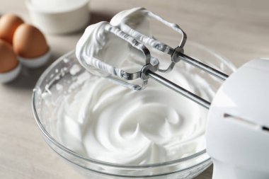 Masada çırpılmış krema ve çırpılmış çırpılmış çırpmalı el çırpıcısı, yakın plan.