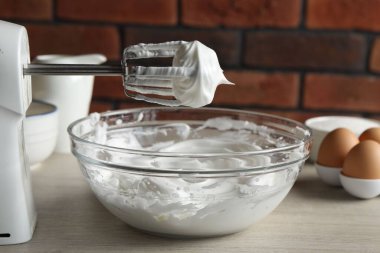 Çırpılmış çırpılmış çırpılmış krema ve çırpılmış kremayla el çırpıcısı tuğla duvara karşı, yakın plan.