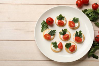Krem peynirli krakerler, domatesler ve maydanozlu beyaz ahşap masa, düz yatak. Metin için boşluk