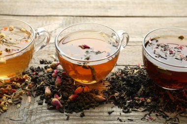 Tahta masada farklı bitki çayları ve kuru yapraklar, yakın plan.