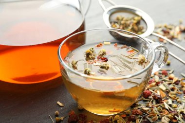 Lezzetli bitkisel çay ve kuru yapraklar siyah masada, yakın plan.