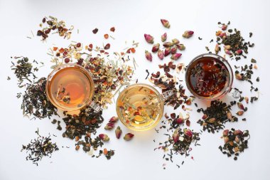Beyaz arka planda farklı bitkisel çaylar ve kuru yapraklar.