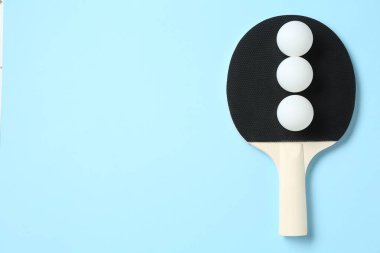 Masa tenisi raketi ve toplar açık mavi arka planda, üst manzara. Metin için boşluk
