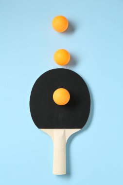 Masa tenisi raketi ve toplar açık mavi arkaplanda, düz yatıyordu