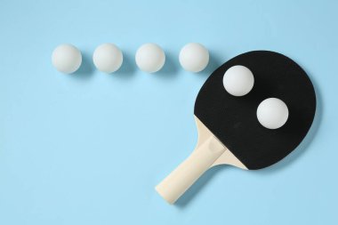 Masa tenisi raketi ve toplar açık mavi arkaplanda, düz yatıyordu