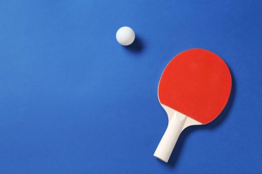 Masa tenisi raketi ve top mavi arka planda, üst manzara. Metin için boşluk