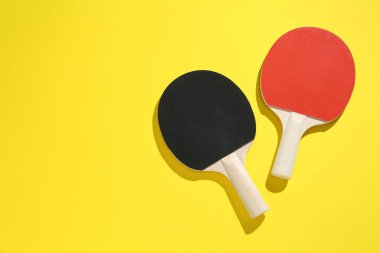 Sarı arka planda pinpon raketleri, üst manzara. Metin için boşluk