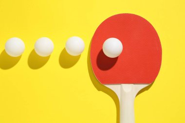 Masa tenisi raketi ve toplar sarı arka planda, düz yatıyordu