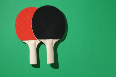 Yeşil arka planda pinpon raketleri, üst manzara. Metin için boşluk