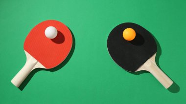 Yeşil arka planda pinpon raketleri ve topları düz yatıyordu.