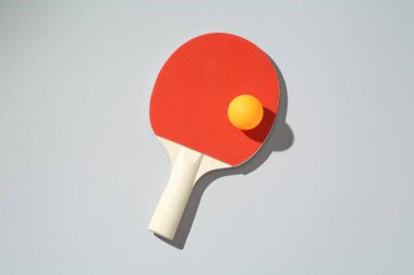 Masa tenisi raketi ve topu arka planda, üst görünümde.