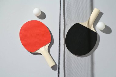 Masa tenisi raketleri, toplar ve net ışık arkaplanı, düz yatıyordu
