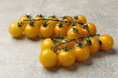 Gri masada olgun sarı kiraz domatesleri, yakın plan.