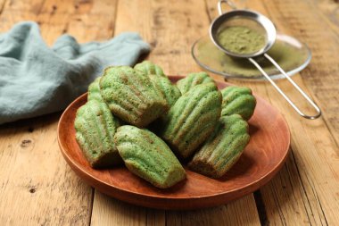 Lezzetli madelaine kekleri ve kibrit tozu ahşap masada, yakın plan.