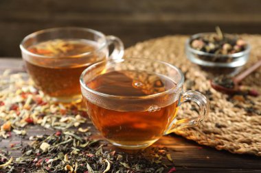 Bitki çayı ve kuru yaprakları ahşap masaya serpmek, yakın plan.