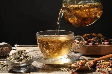 Ahşap masada çaydanlıktan fincana bitkisel çay dökmek, yakın plan. Metin için boşluk