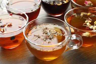 Ahşap masada cam fincanlarda Aromatik bitki çayı, yakın plan.