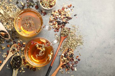 Aromatik bitki çayı ve kuru yapraklar gri masada, düz yerde. Metin için boşluk