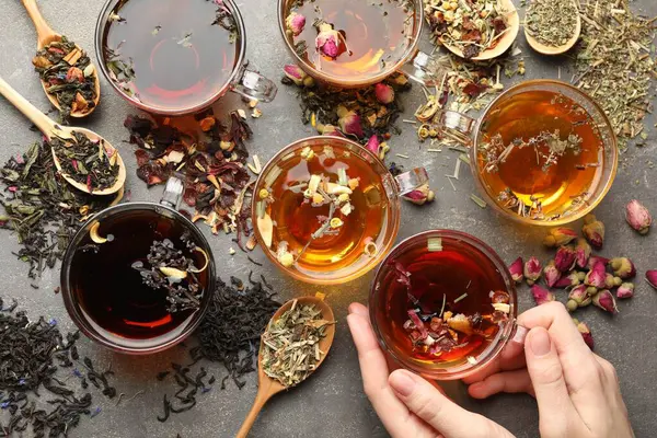 Gri masada aromatik bitki çayı, kuru yapraklar ve çiçekli bir kadın.